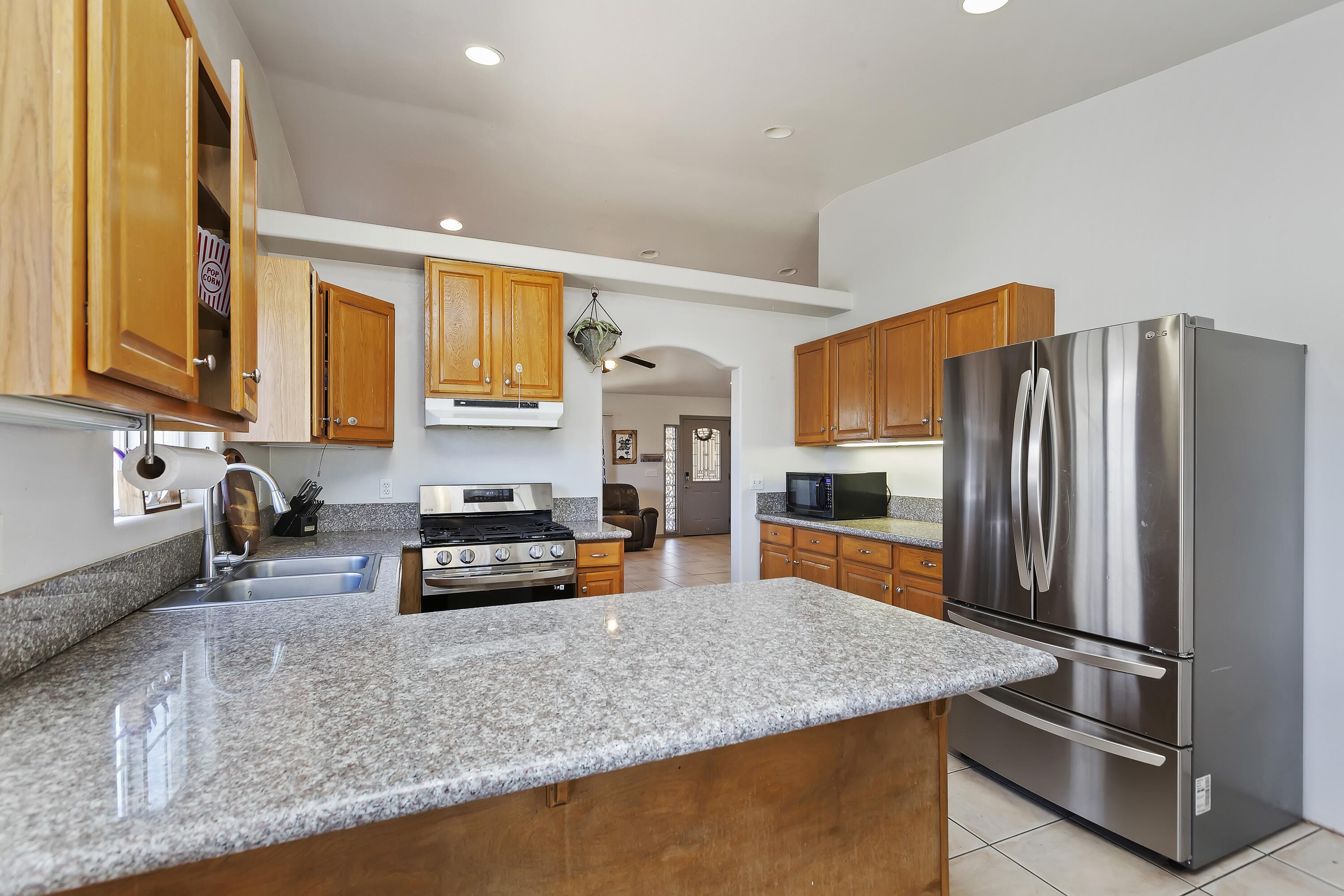 7482 Apache Trail Yucca Valley, CA 92284 - Photo 14 of 38 a kitchen with stainless steel appliances granite countertop a refrigerator a stove and a sink with wooden floor