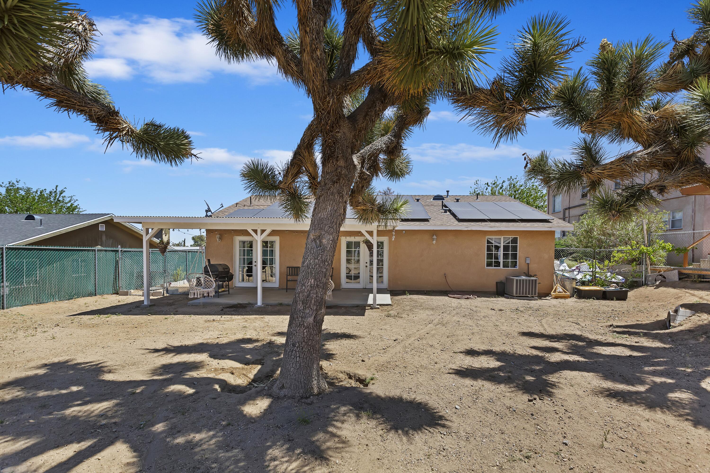 7482 Apache Trail Yucca Valley, CA 92284 - Photo 38 of 38 a front view of a house with a dirt yard and a large tree
