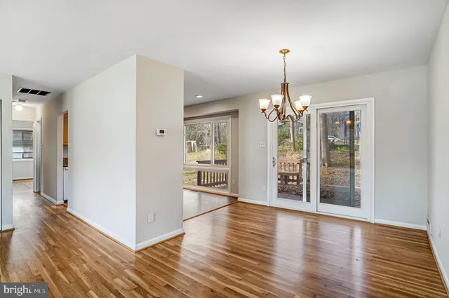 a view of a hallway with wooden floor and a dining room