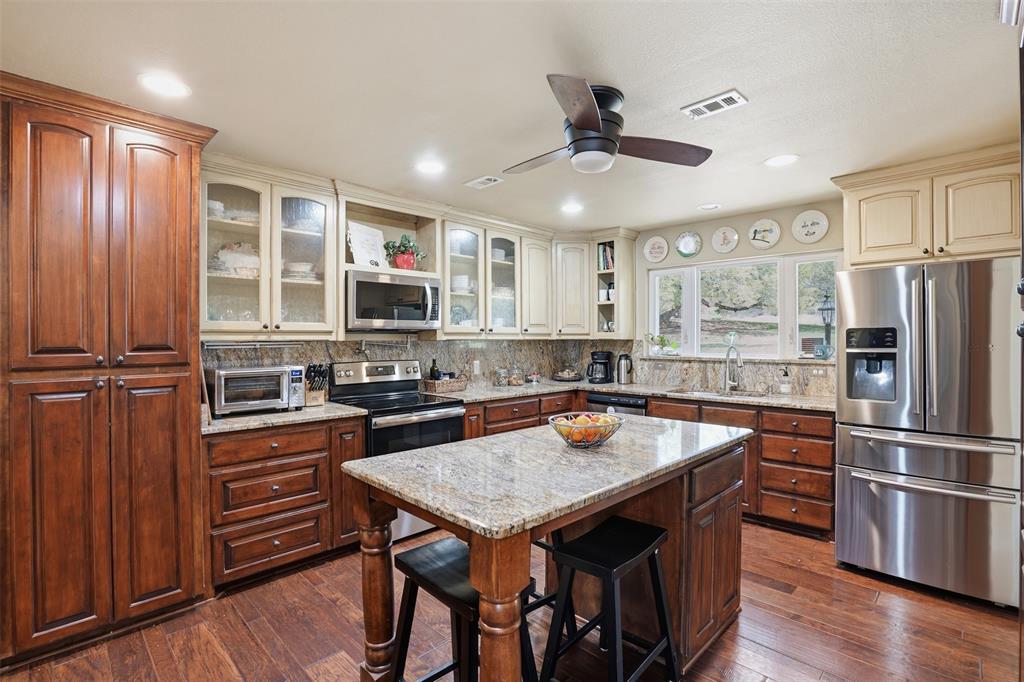 5014 Mohawk Court DeCordova, TX 76049 - Photo 11 of 36 a kitchen with stainless steel appliances granite countertop a stove refrigerator and microwave