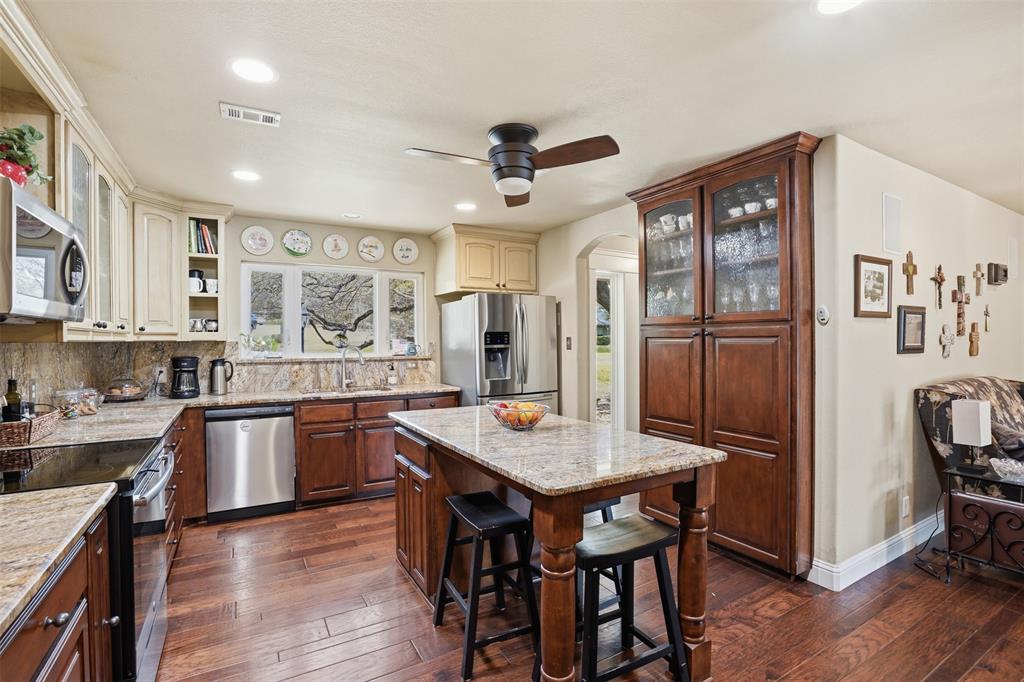 5014 Mohawk Court DeCordova, TX 76049 - Photo 10 of 36 a kitchen with stainless steel appliances granite countertop a table chairs refrigerator and sink