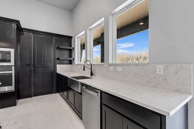 a large kitchen with stainless steel appliances a large center island a stove a sink a dining table and chairs