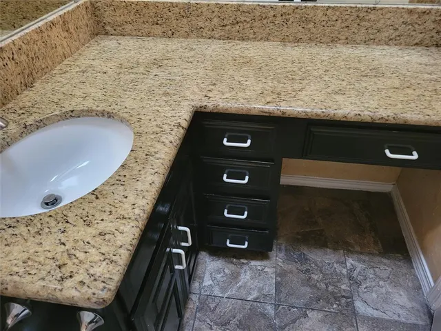 a bathroom with a granite countertop sink a mirror and shower