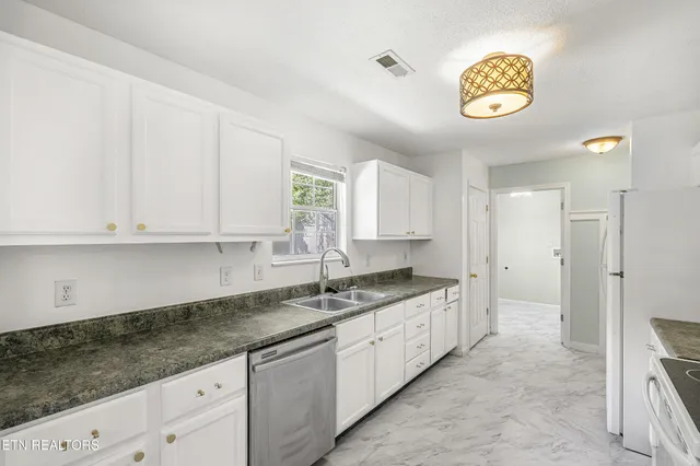 a kitchen with granite countertop white cabinets and stainless steel appliances