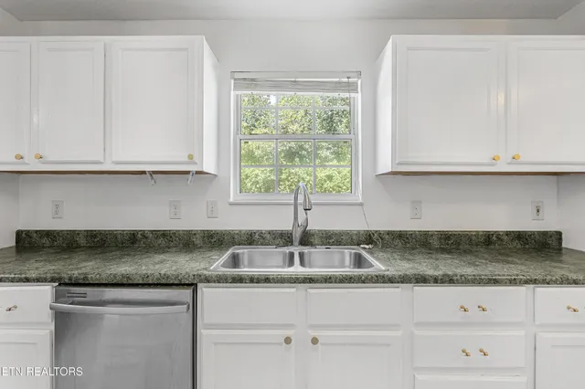 a kitchen with granite countertop white cabinets and a sink