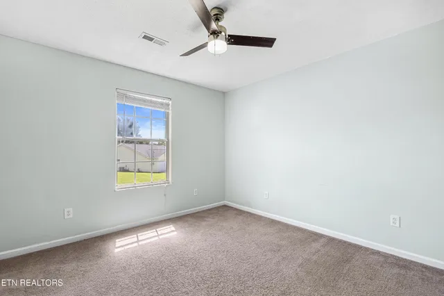 an empty room with a window and ceiling fan