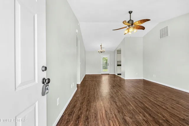 a view of a hallway with wooden floor and chandelier