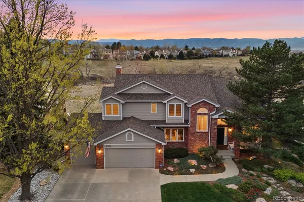 a view of a big house with a big yard plants and large trees