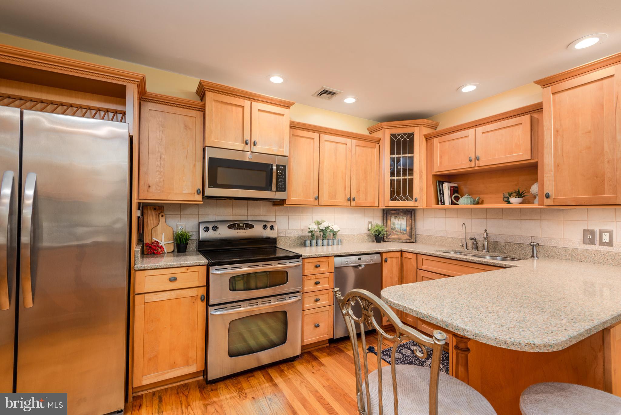 1401 Calvert Road Chester, MD 21619 - Photo 8 of 33 a kitchen with stainless steel appliances granite countertop a sink a stove a refrigerator cabinets and a dining table with wooden floor