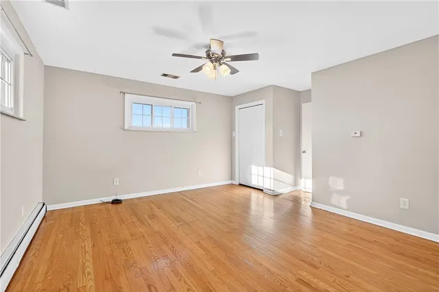 an empty room with wooden floor ceiling fan and windows