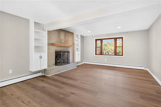 an empty room with windows fireplace and wooden floor
