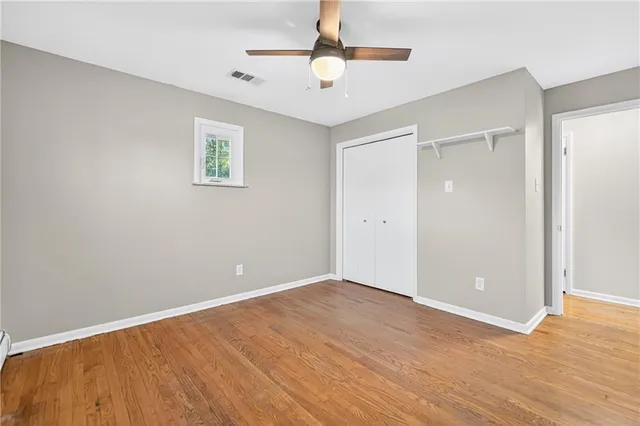 a view of an empty room with window a ceiling fan and wooden floor
