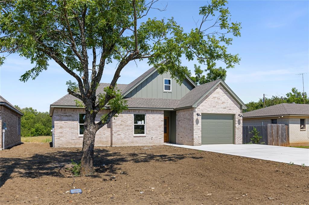 100 Arthur Avenue McGregor, TX 76657 - Photo 2 of 17 View of front of house featuring board and batten siding, brick siding, roof with shingles, and an attached garage
