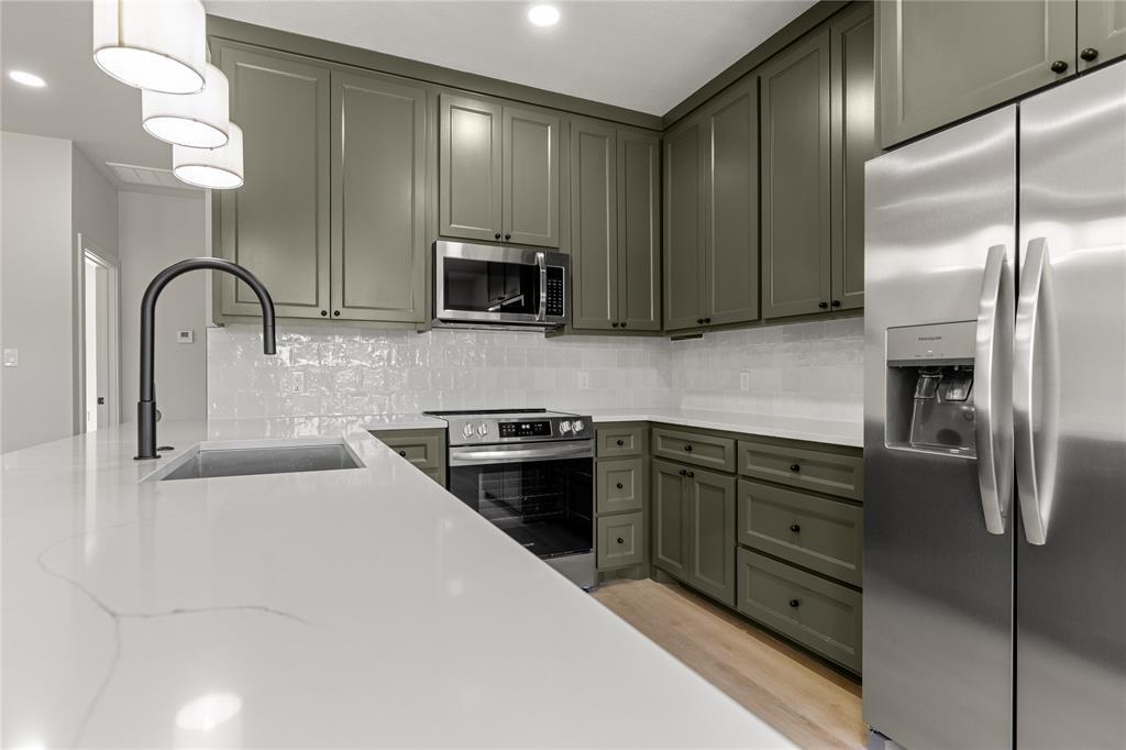 100 Arthur Avenue McGregor, TX 76657 - Photo 4 of 17 Kitchen with stainless steel appliances, decorative backsplash, light stone counters, and light wood-style floors