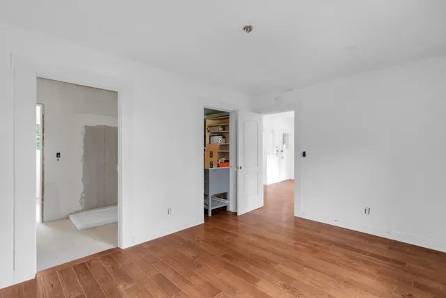 a view of an empty room with wooden floor and closet