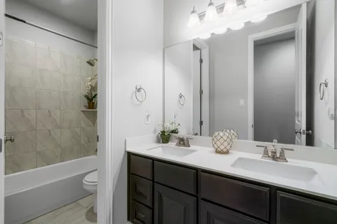 a bathroom with a double vanity sink toilet and shower
