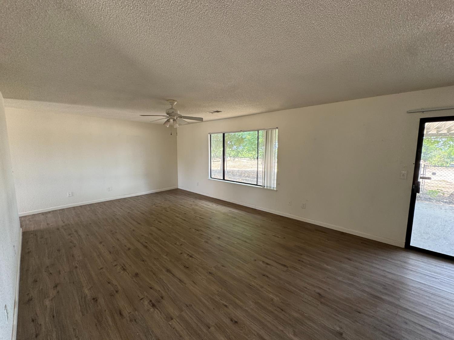 21293 East American Avenue Reedley, CA 93654 - Photo 3 of 19 an empty room with wooden floor and windows
