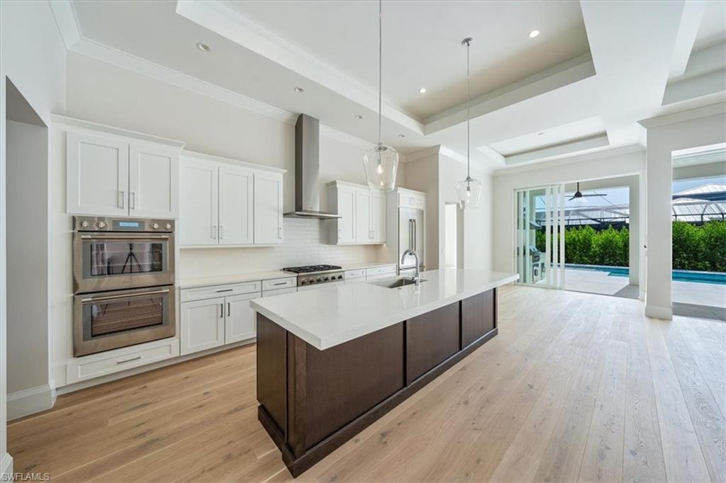 23511 Coconut Road Estero, FL 34134 - Photo 11 of 50 a large kitchen with stainless steel appliances a stove a sink dishwasher a refrigerator white cabinets and wooden floor