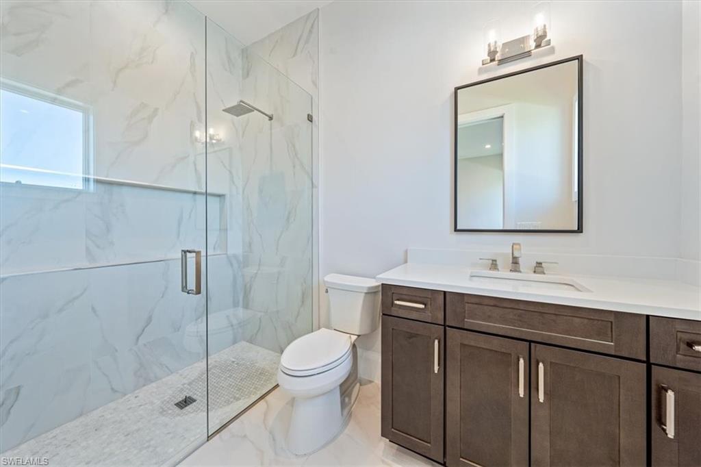 23511 Coconut Road Estero, FL 34134 - Photo 28 of 50 a bathroom with a toilet sink vanity and mirror