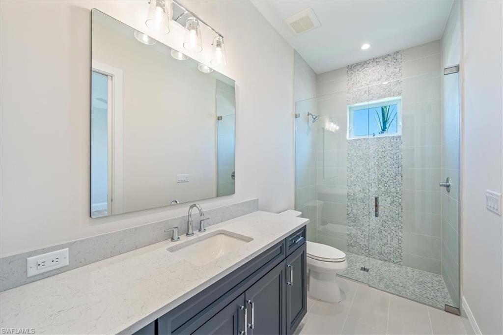 23511 Coconut Road Estero, FL 34134 - Photo 36 of 50 a bathroom with a sink a toilet a shower and a mirror