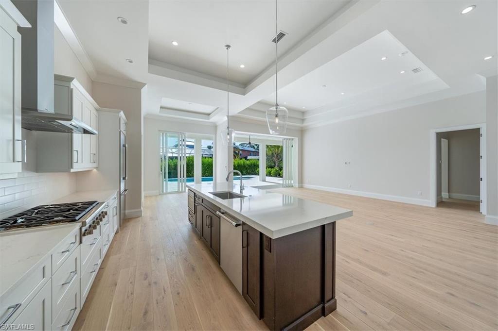 23511 Coconut Road Estero, FL 34134 - Photo 10 of 50 a kitchen with stainless steel appliances a kitchen island hardwood floor sink stove and wooden floor