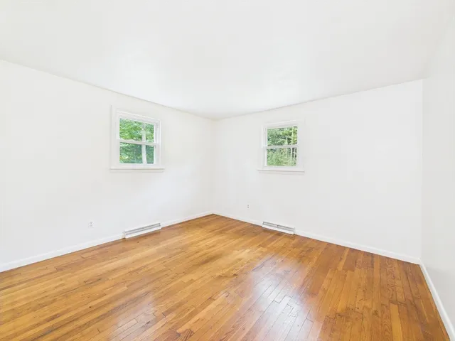 an empty room with wooden floor and window
