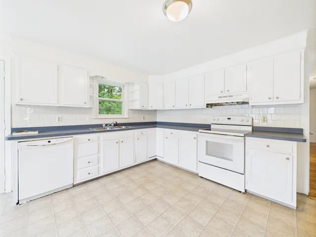 a kitchen with granite countertop white cabinets white stainless steel appliances with a sink and dishwasher