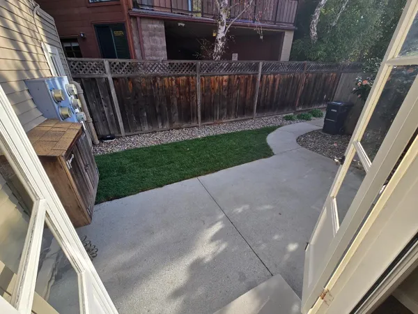 a view of backyard with wooden fence and large trees