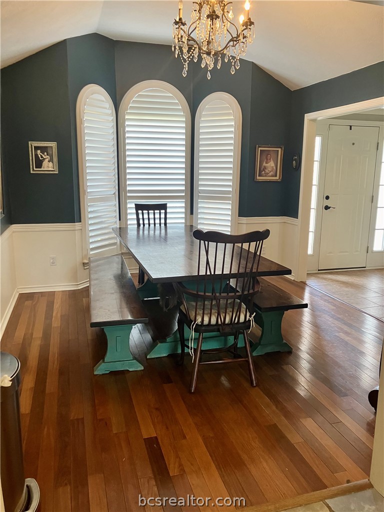 5660 Falling Water Bryan, TX 77808 - Photo 16 of 27 Dining area featuring hardwood / wood-style floors, vaulted ceiling, and an inviting chandelier