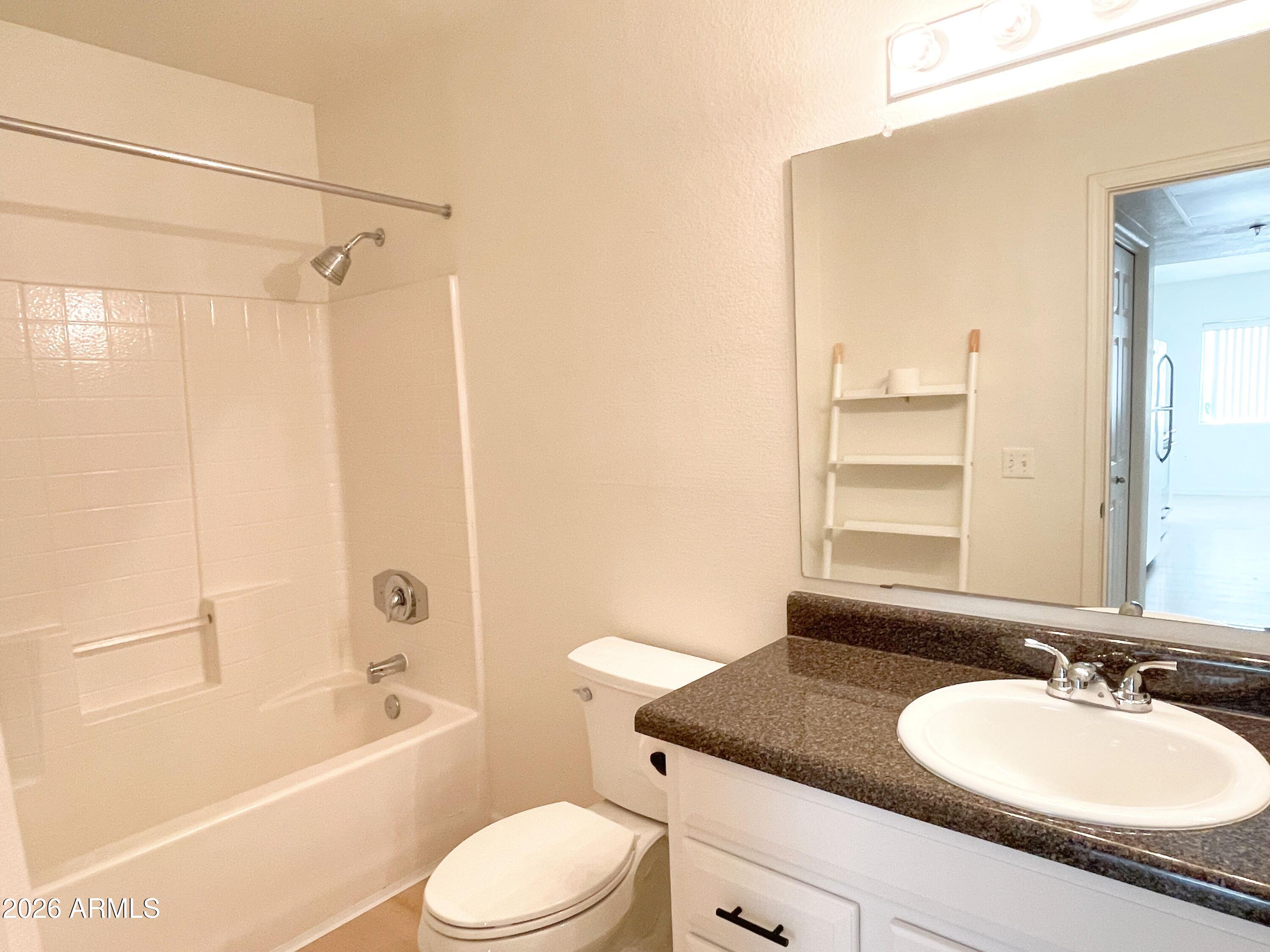1295 North Ash Street, Unit 828 Gilbert, AZ 85233 - Photo 18 of 24 a bathroom with a granite countertop sink toilet mirror vanity and bathtub
