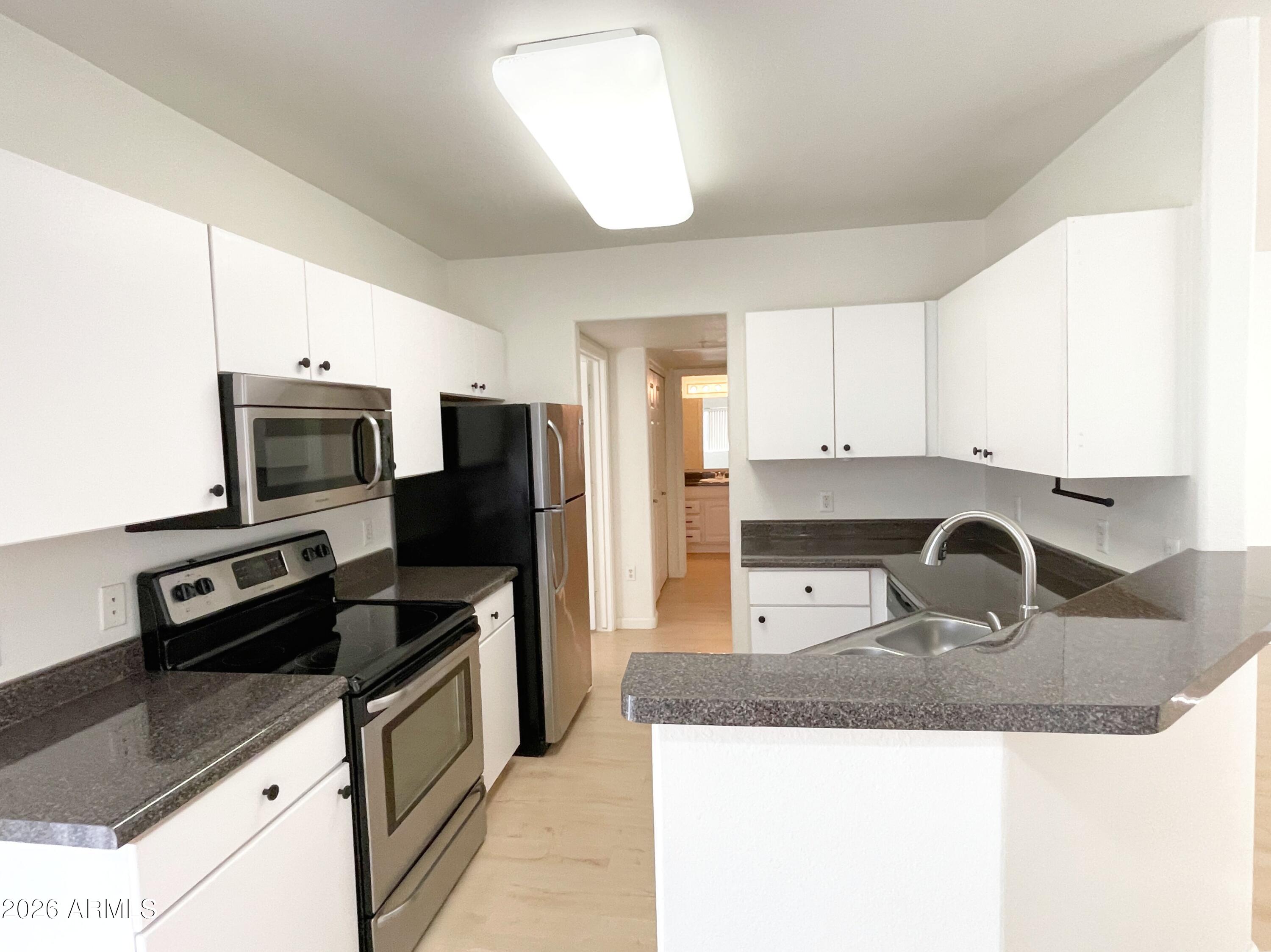 1295 North Ash Street, Unit 828 Gilbert, AZ 85233 - Photo 6 of 24 a kitchen with stainless steel appliances granite countertop a sink refrigerator and microwave