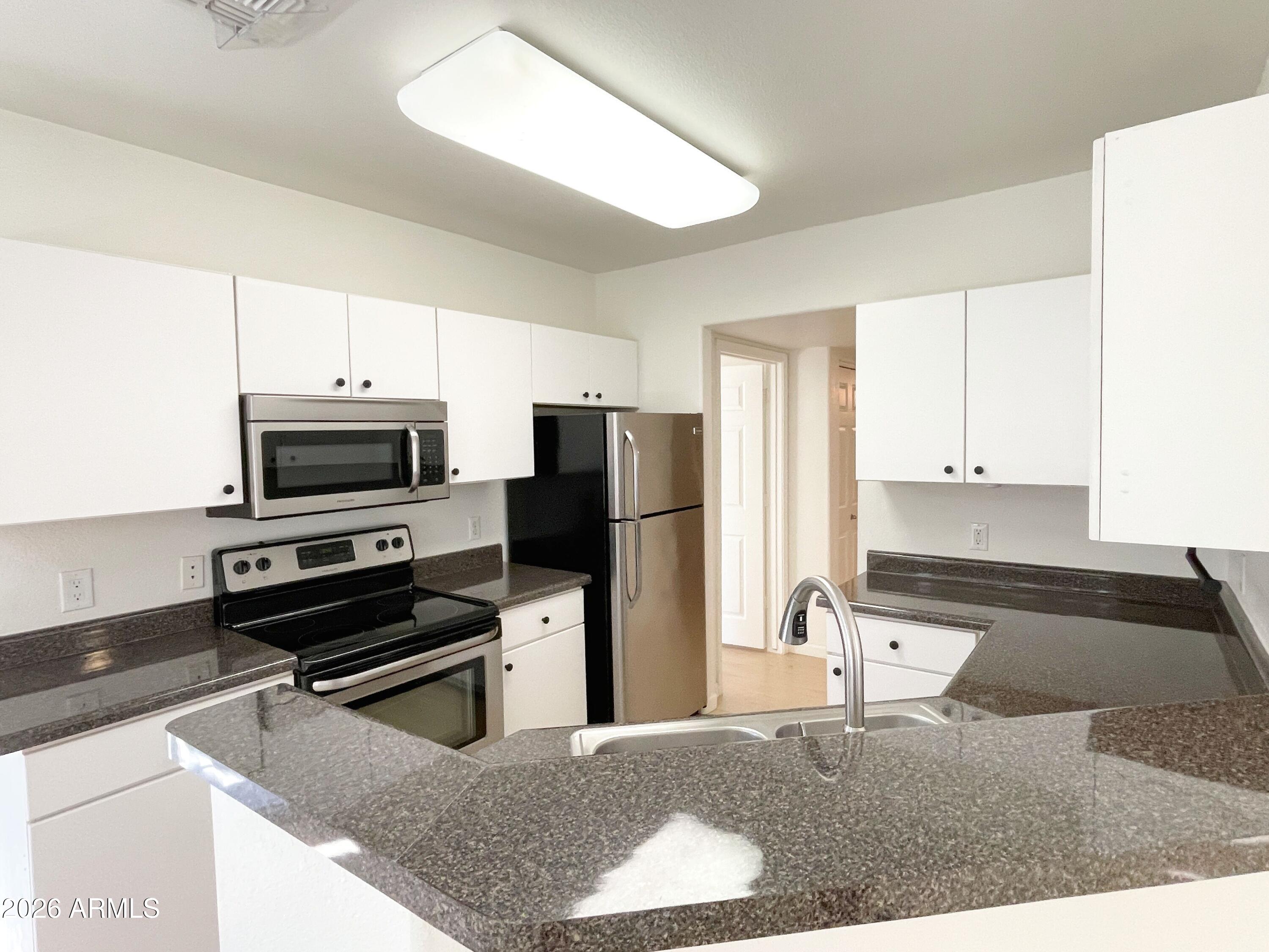 1295 North Ash Street, Unit 828 Gilbert, AZ 85233 - Photo 7 of 24 a kitchen with kitchen island a counter top space cabinets stainless steel appliances and a window