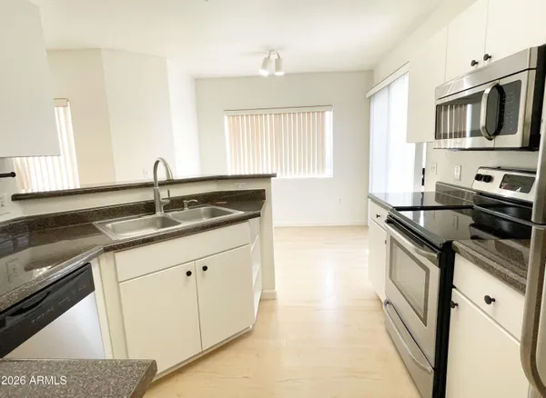 a kitchen with granite countertop a sink stainless steel appliances and cabinets