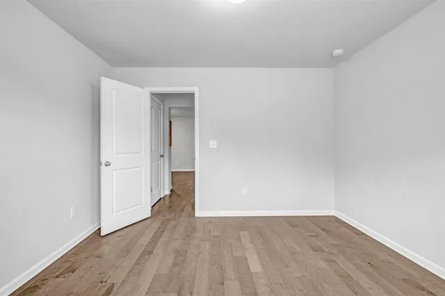 a view of an empty room with wooden floor and closet