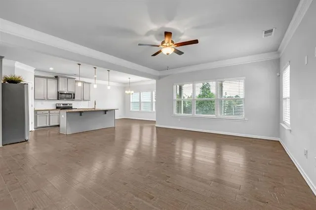 a view of an empty room with a window and wooden floor