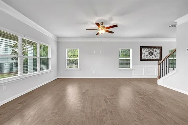a view of an empty room with a window and wooden floor