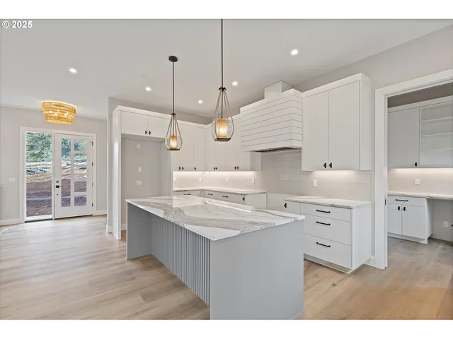 a kitchen that has a lot of cabinets in it and wooden floors