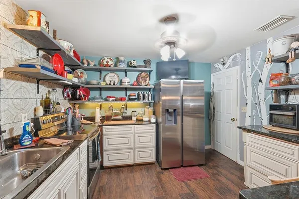 a kitchen with stainless steel appliances a refrigerator a sink and wooden floor