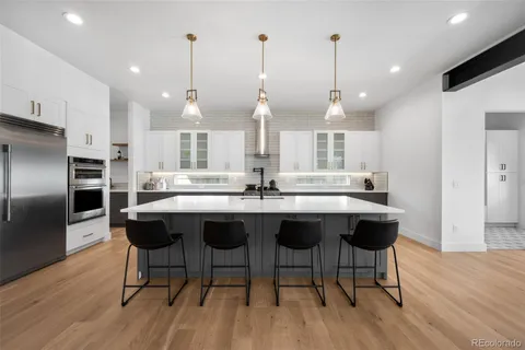 a kitchen with stainless steel appliances kitchen island granite countertop a table chairs in it and wooden floors