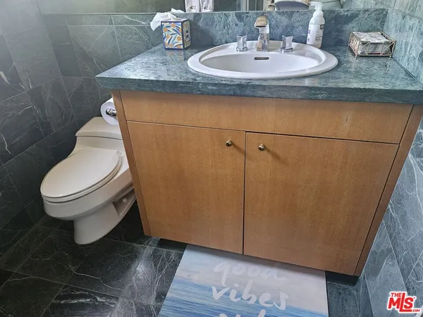 a bathroom with a granite countertop sink and a toilet
