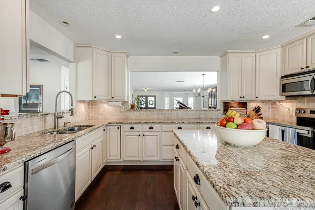 a kitchen with stainless steel appliances a sink dishwasher and white cabinets with wooden floor