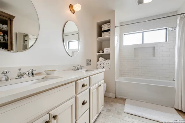 a bathroom with a double vanity sink mirror and a bathtub