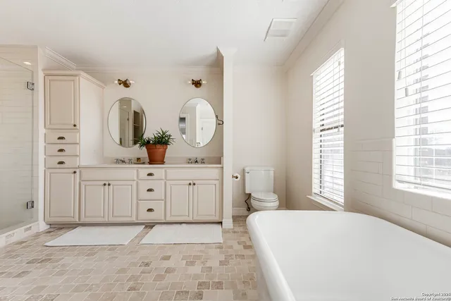 a room with a bed a mirror on the dresser and a window