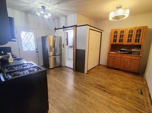 a kitchen with stainless steel appliances granite countertop a refrigerator a stove a sink dishwasher a dining table and chairs with wooden floor