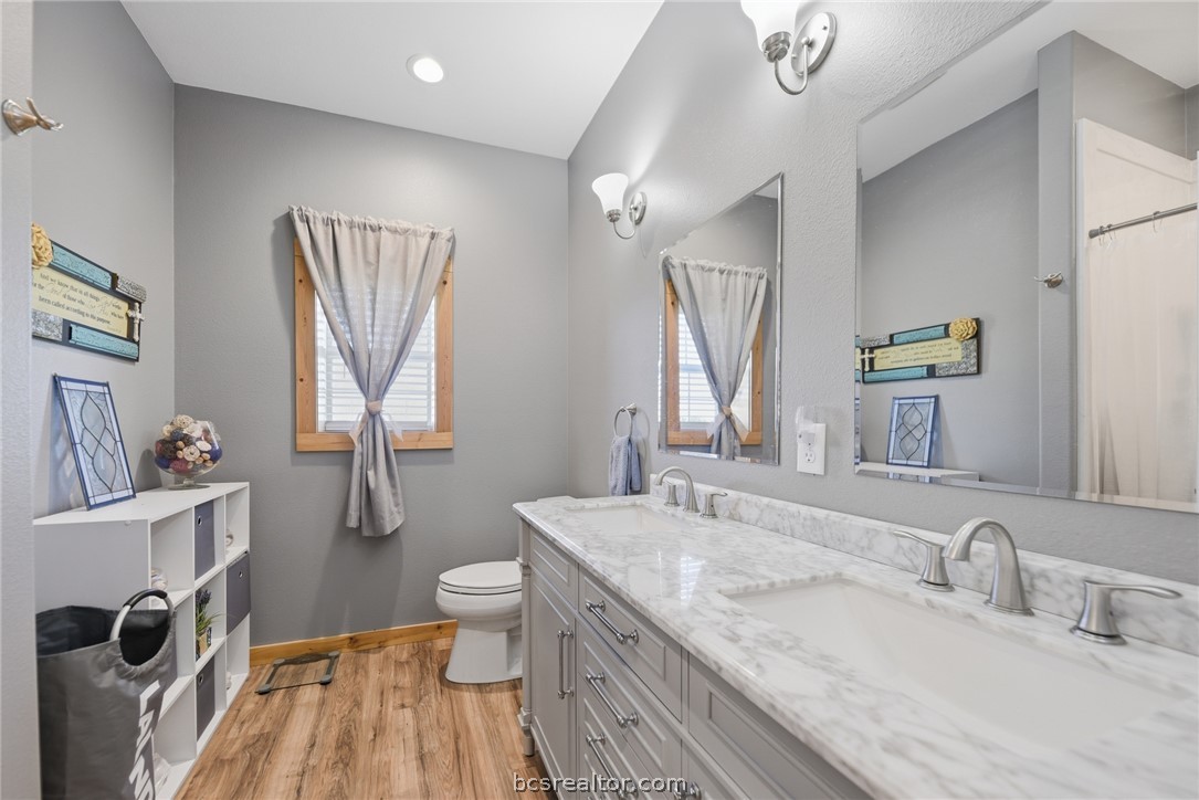 126 South Berlin Road Brenham, TX 77833 - Photo 20 of 30 a bathroom with a granite countertop sink a toilet a mirror and shower