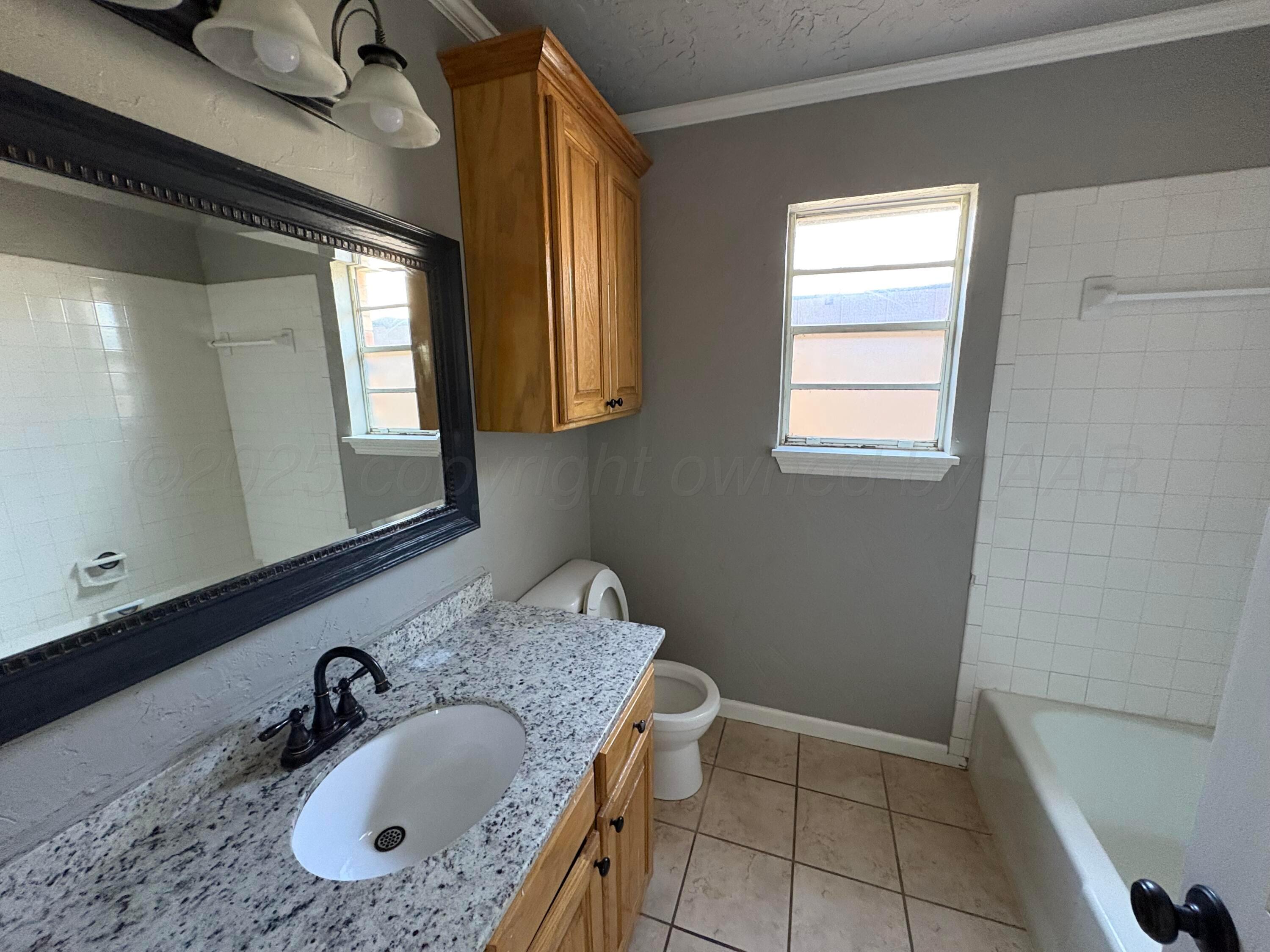 6210 Rutgers Street Amarillo, TX 79109 - Photo 11 of 13 a bathroom with a granite countertop sink and a mirror