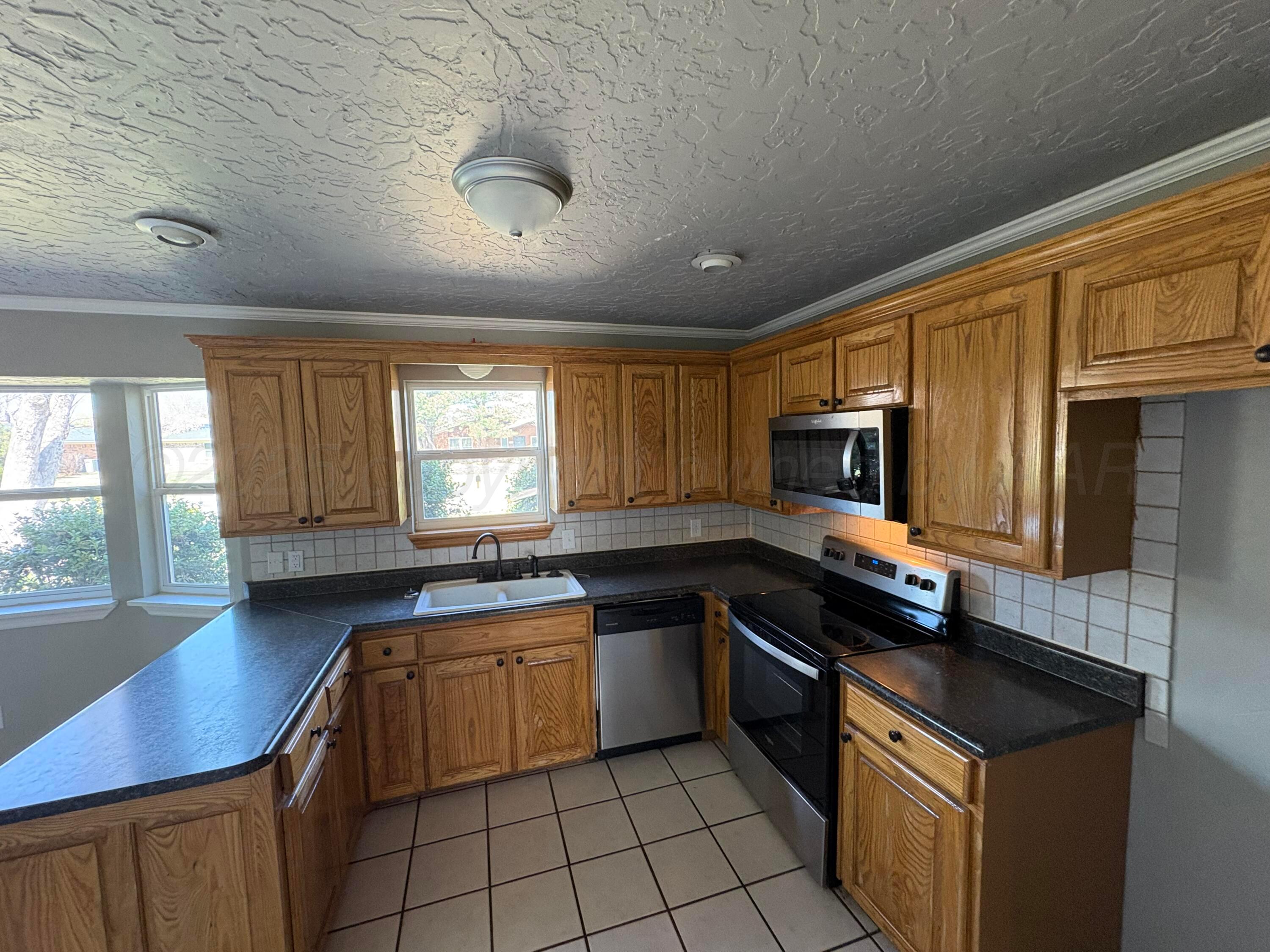 6210 Rutgers Street Amarillo, TX 79109 - Photo 4 of 13 a kitchen with granite countertop a sink stove top oven and cabinets