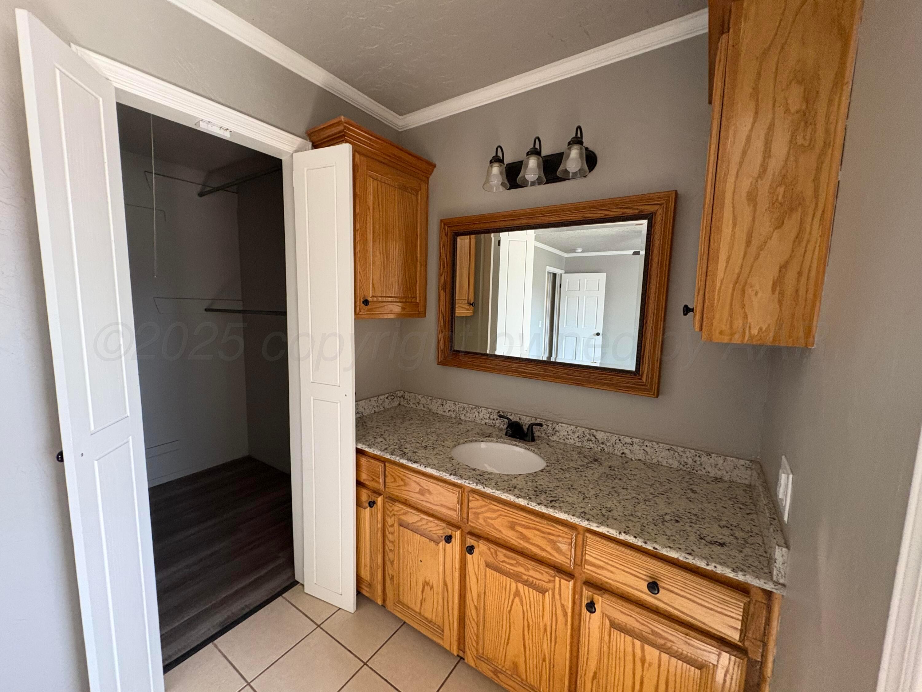 6210 Rutgers Street Amarillo, TX 79109 - Photo 7 of 13 a bathroom with a sink a mirror and a window