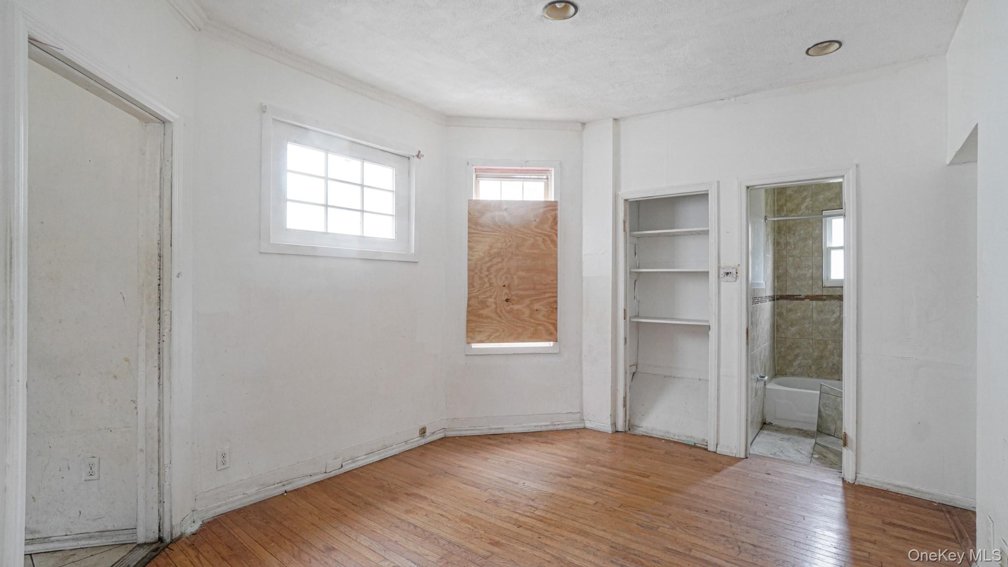 111 South Fulton Avenue Mount Vernon, NY 10550 - Photo 6 of 19 Empty room featuring healthy amount of natural light, hardwood / wood-style floors, and a textured ceiling