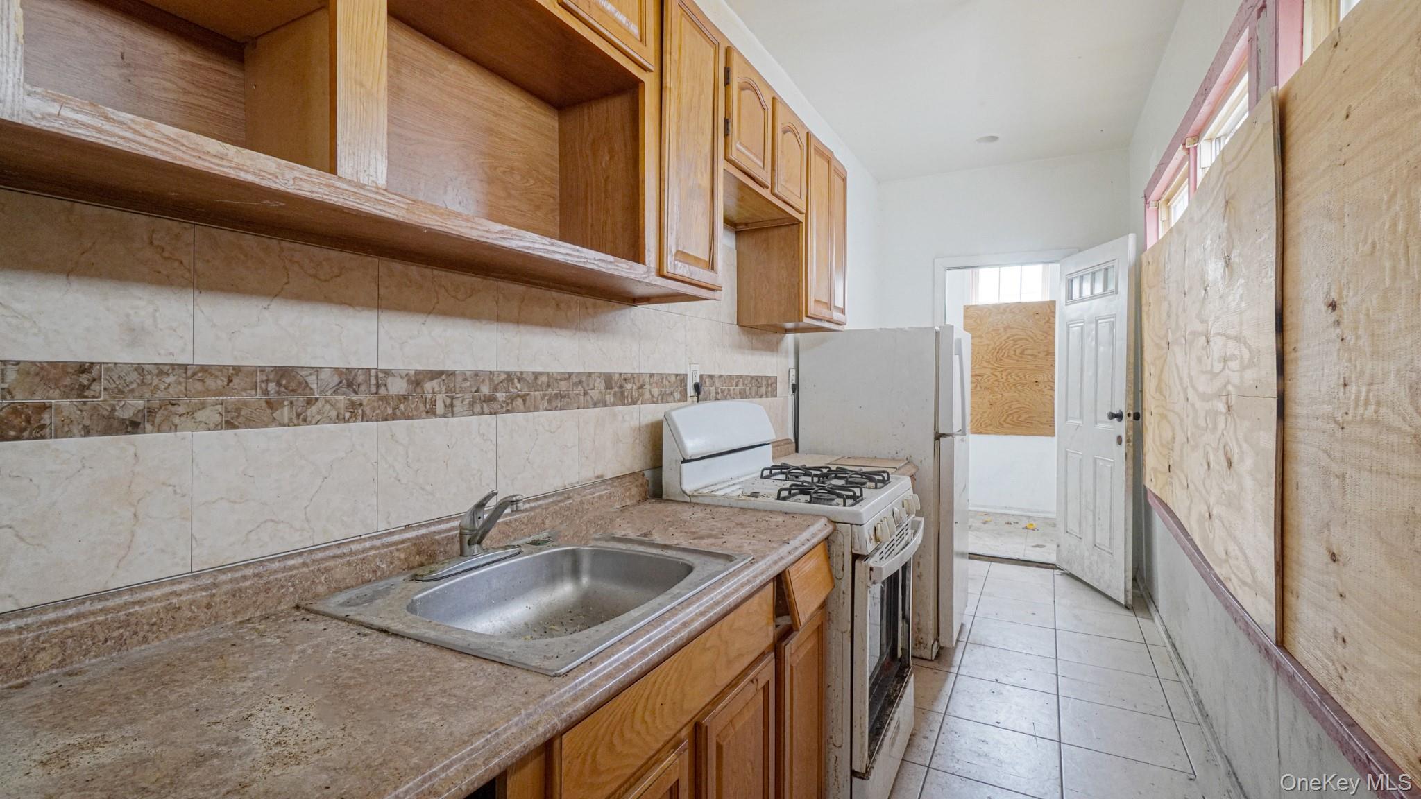 111 South Fulton Avenue Mount Vernon, NY 10550 - Photo 7 of 19 Kitchen with white gas range, brown cabinets, light tile patterned floors, and light countertops